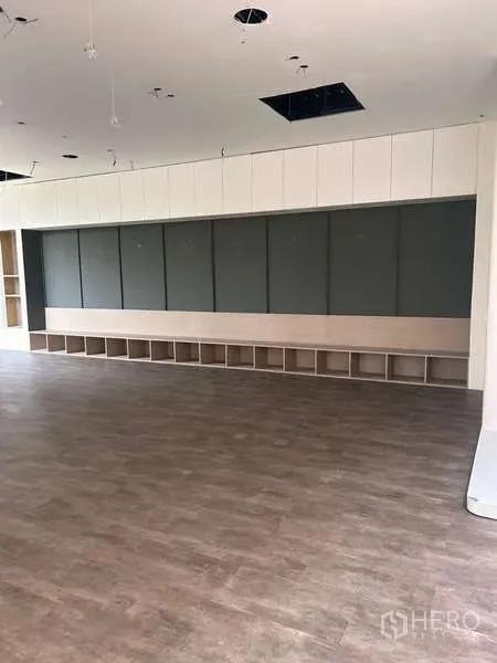 Standalone for rent in Khlong Toei, Bangkok - Wide display wall with built-in storage cubbies and wood-look floors in a flexible space.