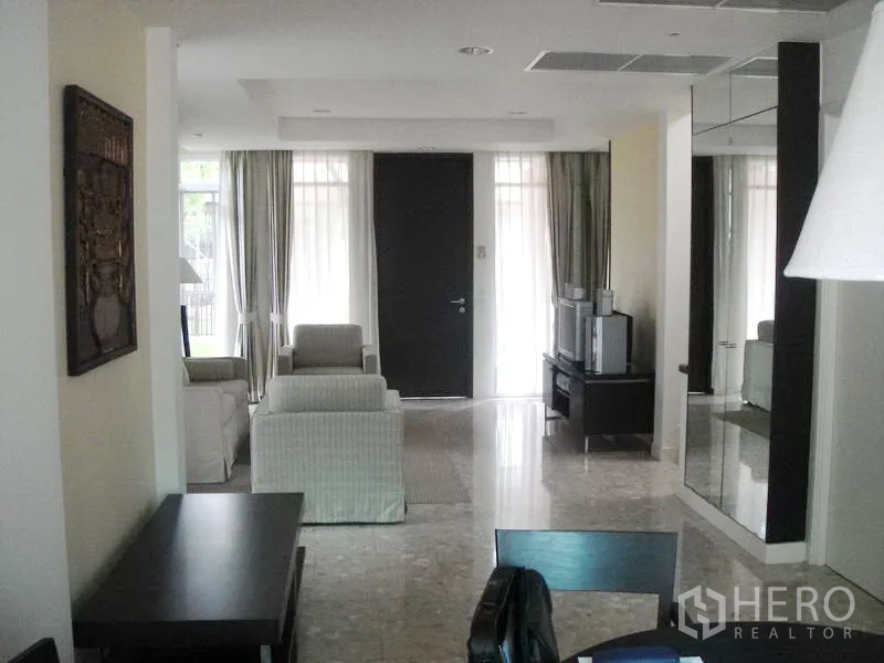 Detached House for rent in Wang Thonglang, Bangkok - Living room facing the front door with sofas, TV cabinet and full-height curtains.