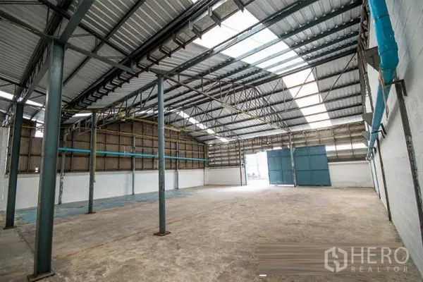 Warehouse for rent - Spacious warehouse interior with steel trusses and skylights providing natural light.