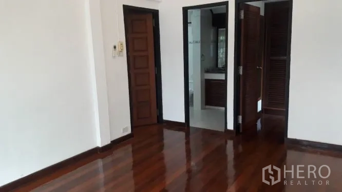 Detached House for rent in Yan Nawa, Bangkok - Bedroom with polished hardwood flooring, white walls, and doors to an en-suite and closet.