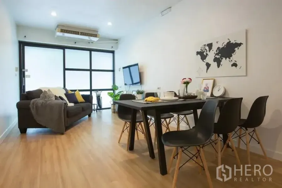 联排别墅 出租在Sathon, Bangkok - 明亮客餐厅，黑框大窗、沙发与餐桌，木地板空间。