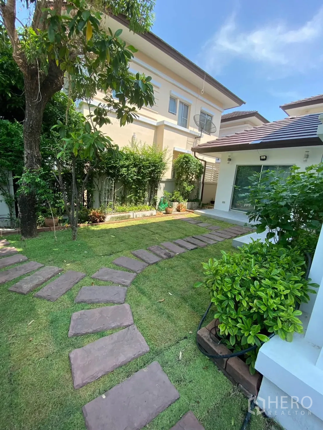 独栋房屋 for rent in Mueang Samut Prakan, Samut Prakan - 私家庭院内弯曲踏步石与成树绿篱。