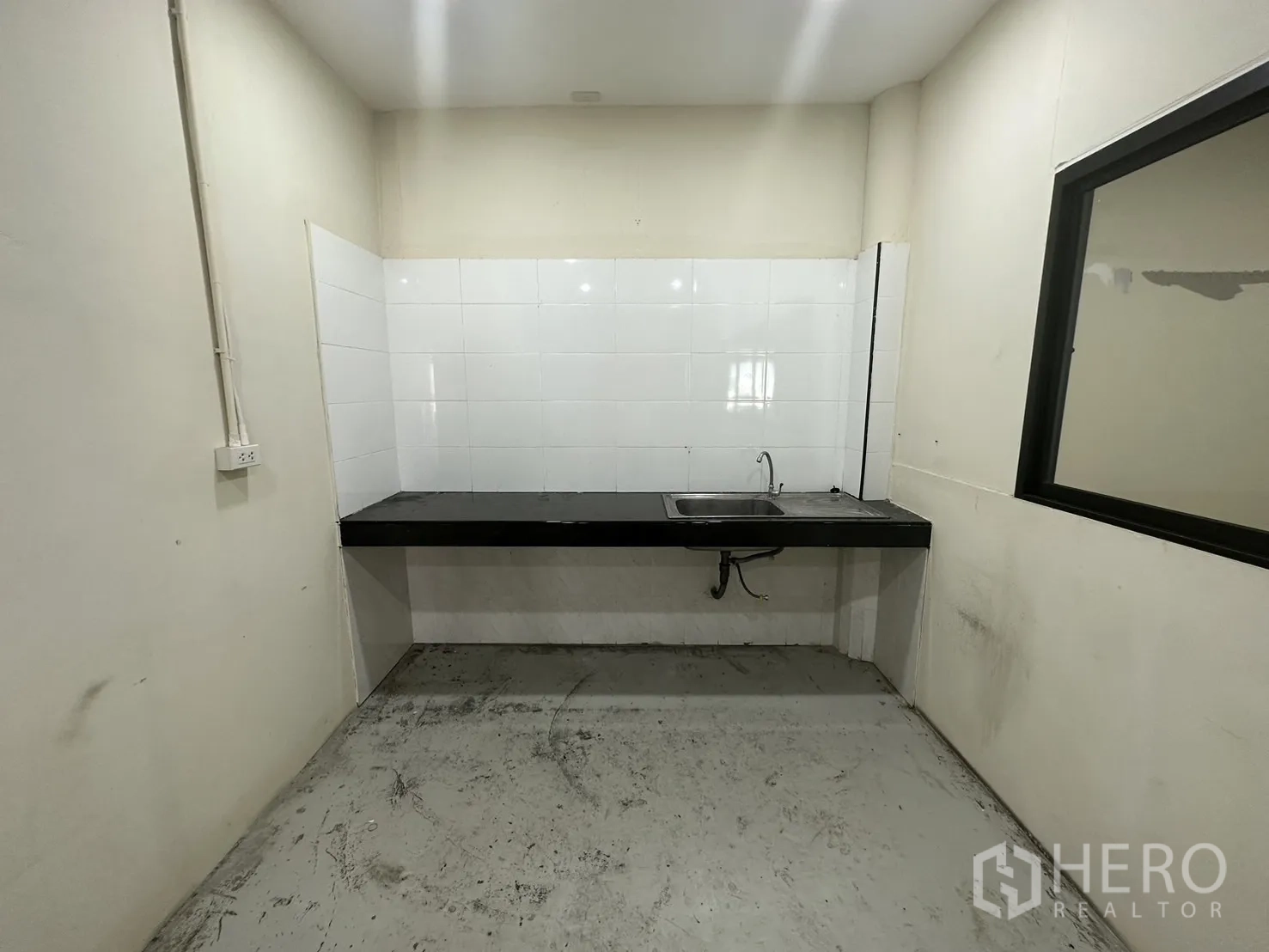Warehouse for rent in Suan Luang, Bangkok - Pantry with sink, black countertop, and white tile backsplash.