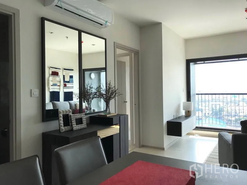 Condominium for rent in Khlong Toei, Bangkok - Bright living area with dining set, large mirror, and balcony city view at Life Condominium.