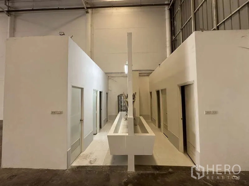 Factory for rent in Khlong Luang, Pathum Thani - Worker restroom block with multiple stalls and a long sink inside the warehouse.
