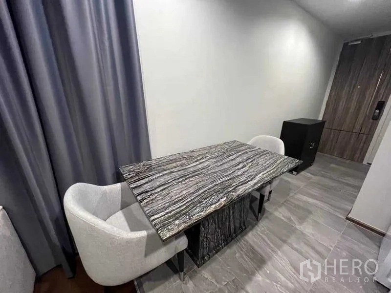公寓 出租在Khlong Toei, Bangkok - 用餐角落，石质餐桌、两把软垫椅与灰色窗帘。