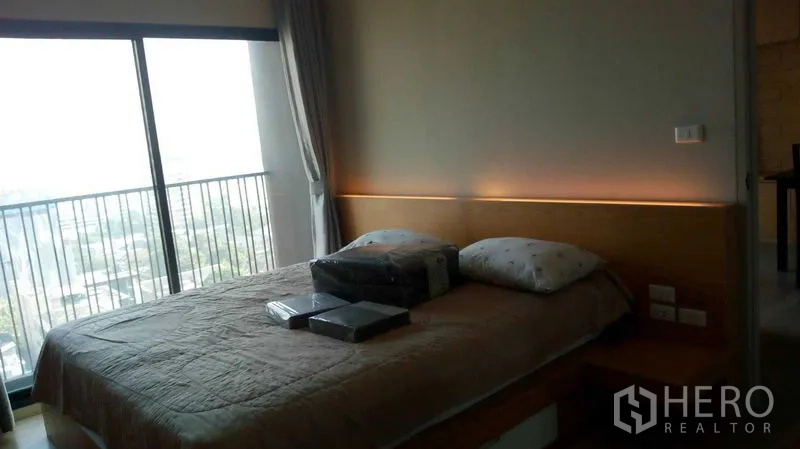 公寓 出租在Watthana, Bangkok - Ekkamai公寓卧室，落地窗与阳台栏杆，床头氛围灯。