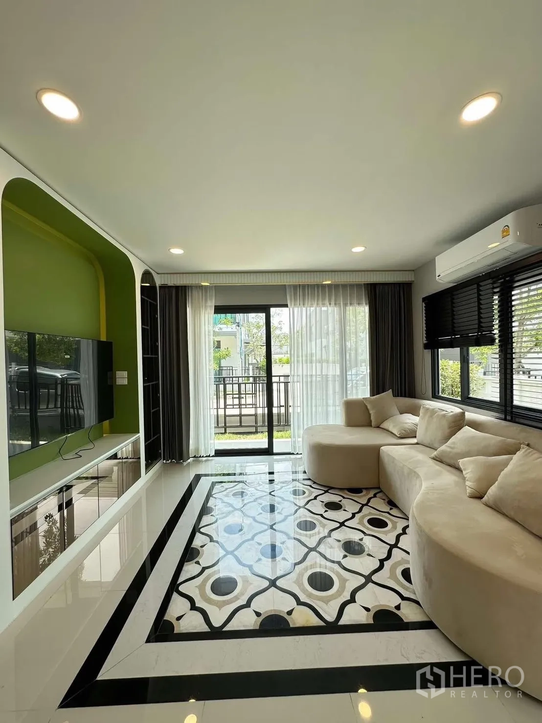 Detached House for rent in Bang Phli, Samut Prakan - Living room with sliding glass doors to the outdoor area and a curved sectional sofa.