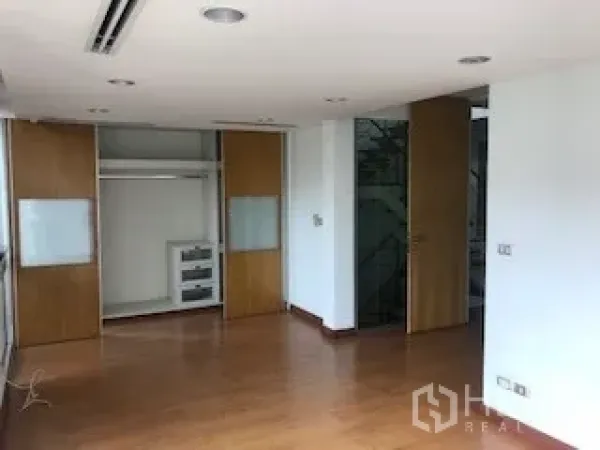 Townhouse for rent or sale in Yan Nawa, Bangkok - Spacious bedroom with built-in sliding wardrobe and wood flooring.