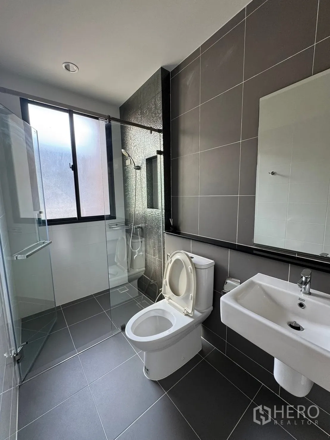 Townhouse for rent in Saphan Sung, Bangkok - Modern bathroom with glass-enclosed shower and dark tiles.