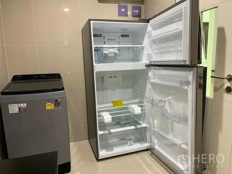 Detached House for rent in Bang Kapi, Bangkok - Utility area with open two-door refrigerator and top-load washing machine