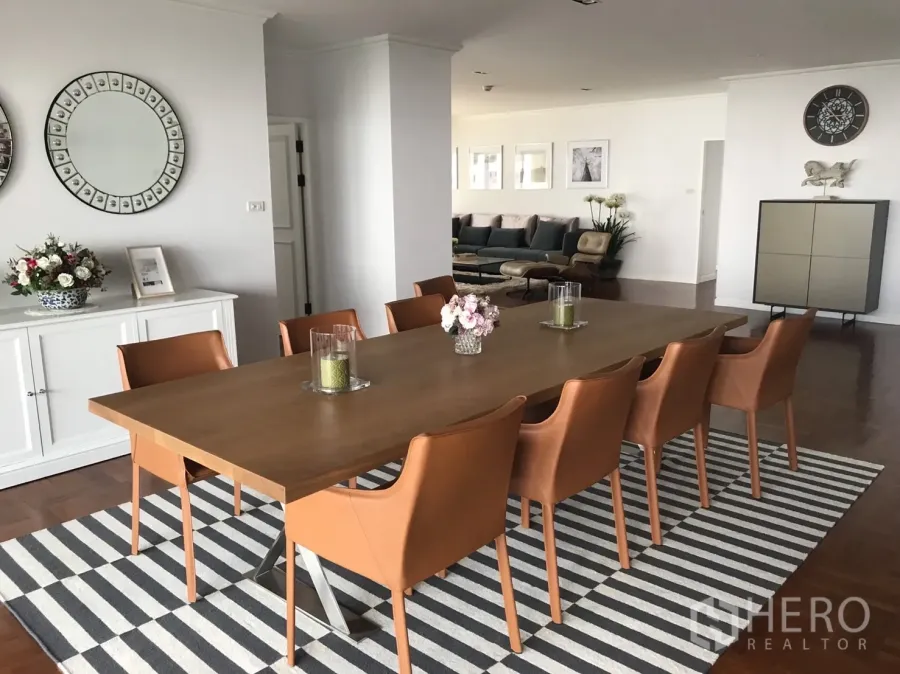 Condominium for rent in Bangkok - Wide view of the dining area with tan leather chairs and sideboard, linked to the living room.
