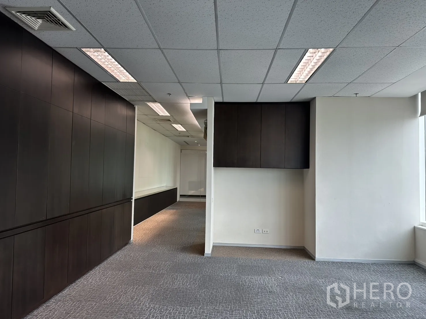Office Space for rent in Watthana, Bangkok - Open workspace with dark built-in storage, suspended cabinets, and drop ceiling lights.