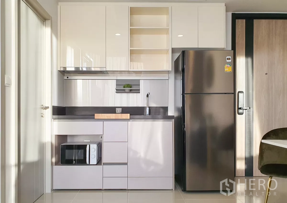 Condominium for rent in Khlong Toei, Bangkok - Compact kitchenette with sink, built‑in storage, microwave and stainless fridge.