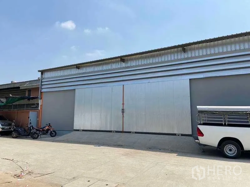 Warehouse for rent in Lam Luk Ka, Pathum Thani - Street-facing metal-clad warehouse with extra-wide sliding doors and loading apron in Lam Luk Ka, Pathum Thani.