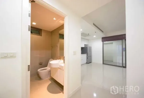 คอนโด ขาย - ห้องน้ำสะอาดติดกับพื้นที่เปิดโล่งและครัวขนาดกะทัดรัดสีขาว