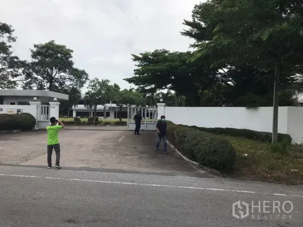โรงงาน ให้เช่าในMueang Chon Buri, Chon Buri - ทางเข้าโรงงานมีกำแพงและประตูรั้วกว้าง พร้อมป้อมยามและต้นไม้จัดสวน