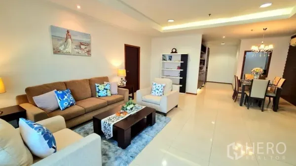 Apartment for rent in Watthana, Bangkok - Bright open-plan living room with sofa set, rug, shelving and recessed lighting.