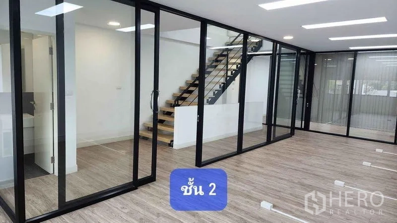 Townhouse for rent in Bueng Kum, Bangkok - Second-floor workspace with full-height glass partitions and an open-tread staircase.