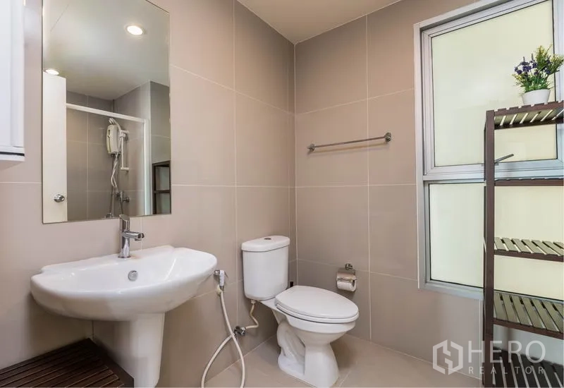 Condominium for rent in Bang Na, Bangkok - Modern bathroom with window, white fixtures, and separate shower area.