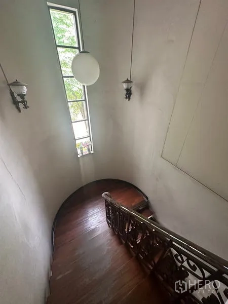 Detached House for sale in Phra Khanong, Bangkok - Curved stairwell with tall vertical window and pendant light.