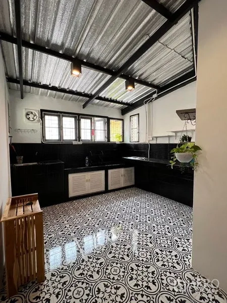 Townhouse for rent in Ratchathewi, Bangkok - Bright kitchen with black cabinetry, patterned floor tiles and a corrugated metal ceiling.