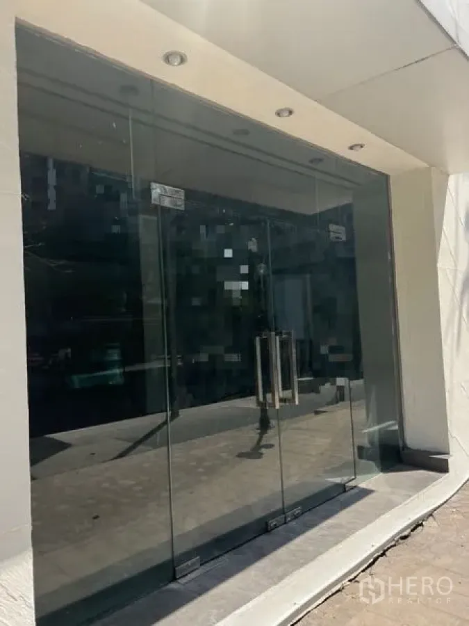 零售空间 出租在Khlong Toei, Bangkok - 临街玻璃门店外立面，双开玻璃门配嵌灯的门廊入口。