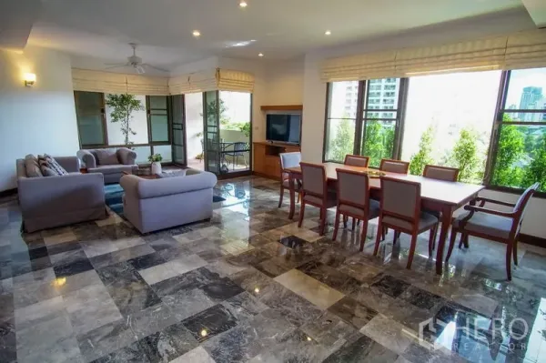 Apartment for rent in Watthana, Bangkok - Spacious lounge and dining area with grey sofas, city views through wide windows, glossy marble flooring, and a balcony corner.