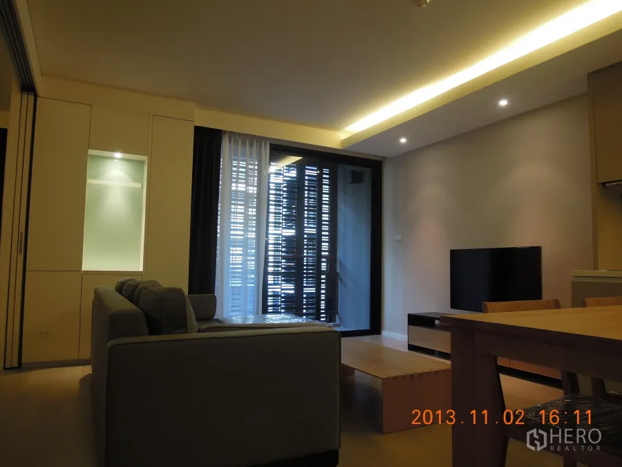 公寓 出租在Watthana, Bangkok - 现代客厅，配沙发、电视、餐桌，连接带百叶遮挡的阳台