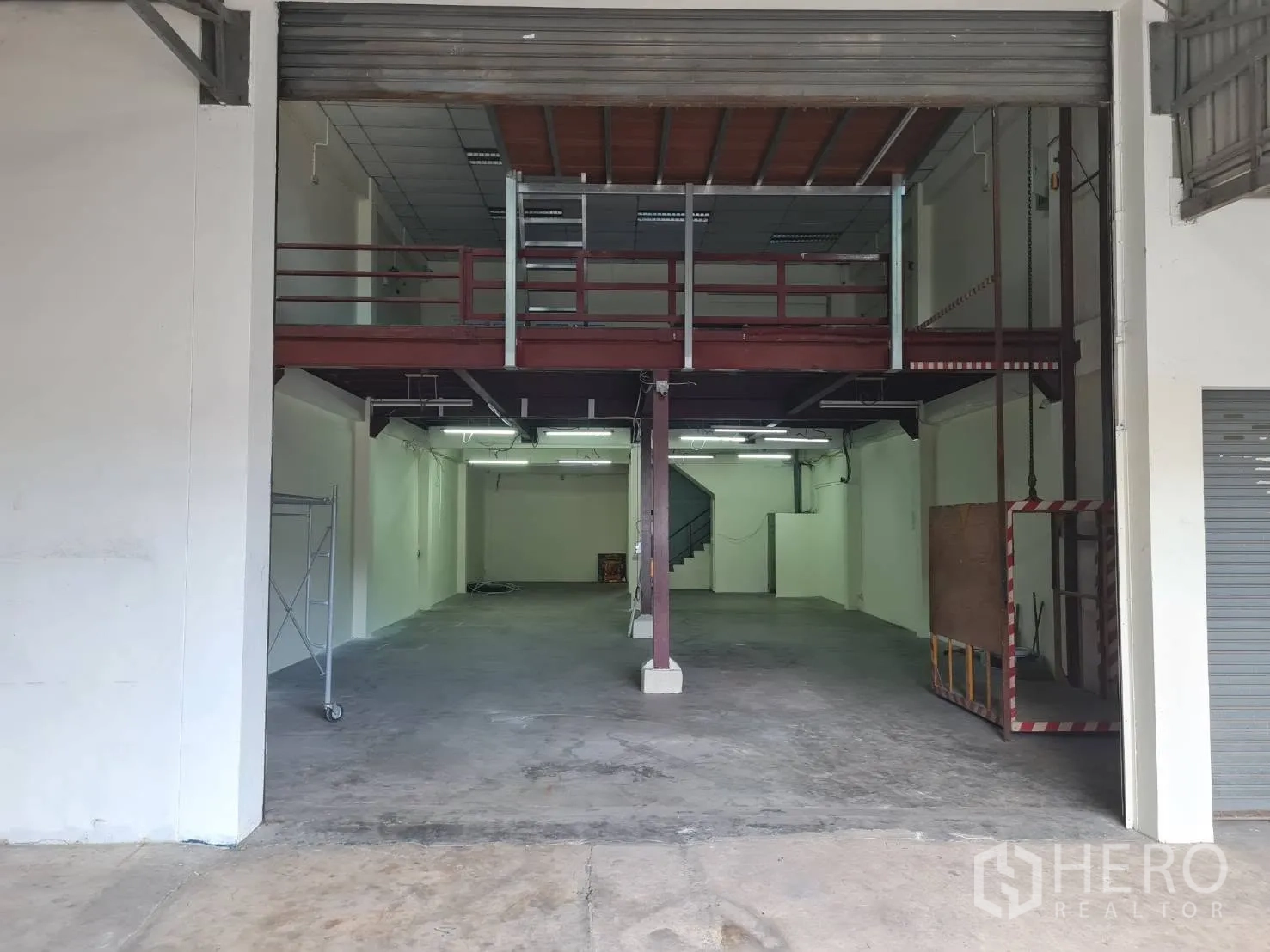 Warehouse for rent in Phra Pradaeng, Samut Prakan - Warehouse hall with concrete floor, mezzanine platform, and shutter entrance.