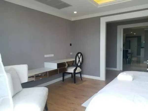 公寓 出租在Bang Rak, Bangkok - 卧室一角，带镜面墙体书桌、饰椅与木地板，通向起居区。