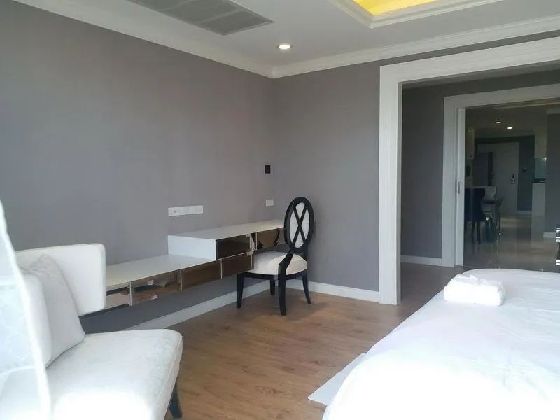 公寓 出租在Bang Rak, Bangkok - 卧室一角，带镜面墙体书桌、饰椅与木地板，通向起居区。