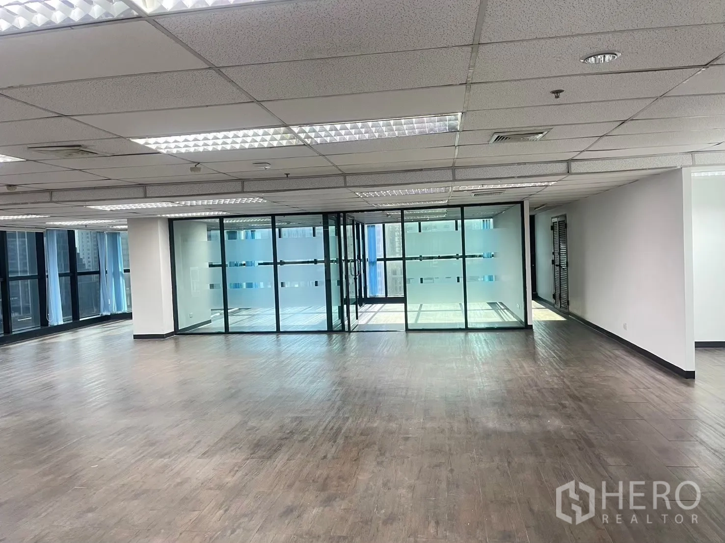 Office Space for rent in Watthana, Bangkok - Spacious workspace facing a glass-enclosed room and wraparound windows.