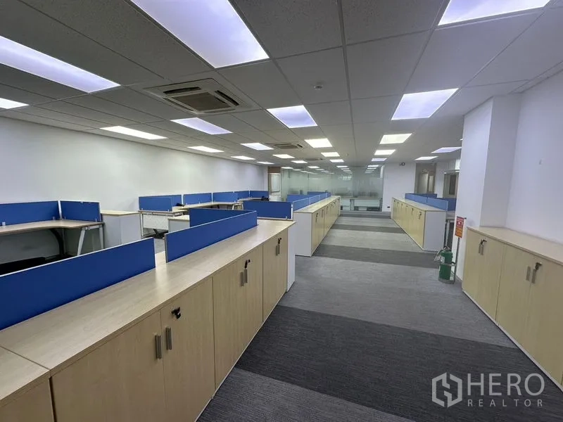 Office Space for rent - Open-plan office with blue-partition workstations, low cabinets, carpet tiles and LED ceiling lights.