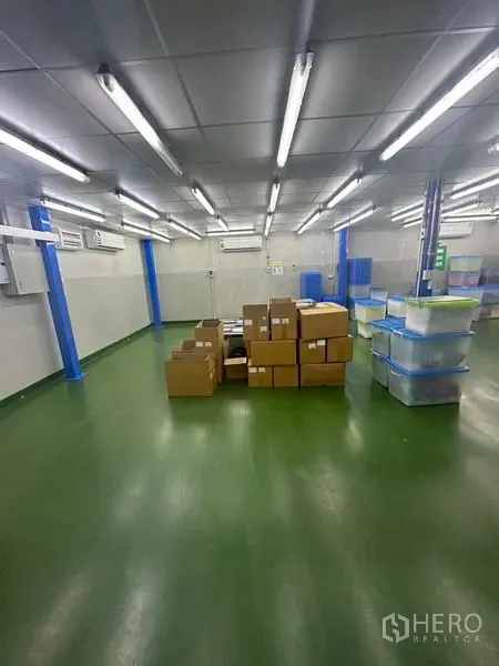 Warehouse for rent or sale in Lam Luk Ka, Pathum Thani - Air‑conditioned production or storage room with green epoxy floor and stacked cardboard boxes.