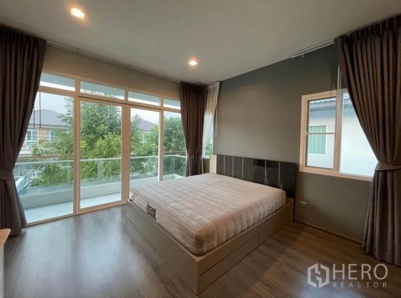 Detached House for rent in Lat Krabang, Bangkok - Master bedroom featuring floor-to-ceiling windows and a long balcony overlooking greenery
