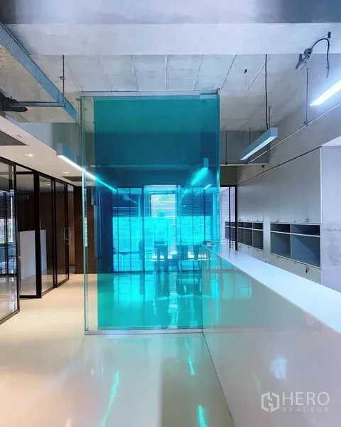 办公空间 出租在Phaya Thai, Bangkok - 现代办公室内景，白色亮面地坪、青色玻璃隔断、外露天花与充足采光。