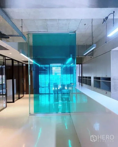 办公空间 出租在Phaya Thai, Bangkok - 现代办公室内景，白色亮面地坪、青色玻璃隔断、外露天花与充足采光。