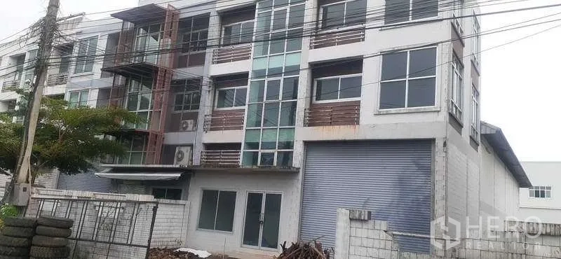 货栈 出租在Pathum Thani - 四层工业建筑，带仓库和大型卷帘门的外立面
