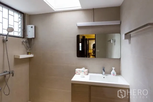 Detached House for rent in Watthana, Bangkok - Bright bathroom with beige tiles, vanity, skylight and walk‑in shower with water heater.