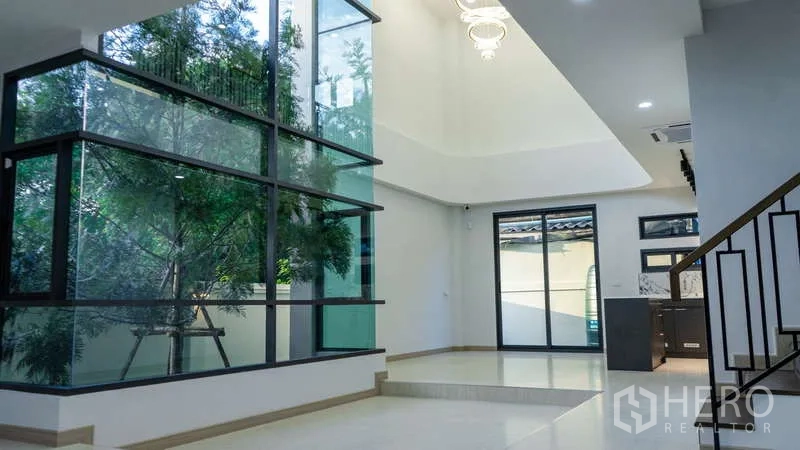 独立式住宅 出租或出售在Suan Luang, Bangkok - 开放客厅，整面大玻璃、吊灯与金属栏杆