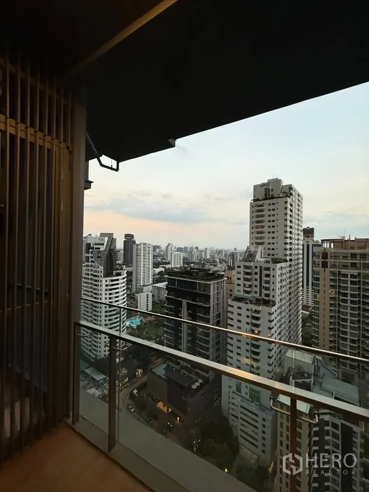 公寓 for rent in Watthana, Bangkok - 高层阳台玻璃护栏，可眺望通罗–艾卡迈城市天际线的黄昏景色。