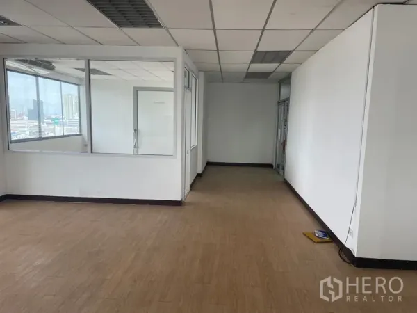 Office Space for rent in Din Daeng, Bangkok - Spacious workspace with suspended ceiling lights, wood floors, and enclosed rooms along a corridor.