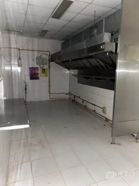 零售空间 出租在Khlong Toei, Bangkok - 后场商用厨房，带不锈钢排烟罩与瓷砖墙面，配备操作台。