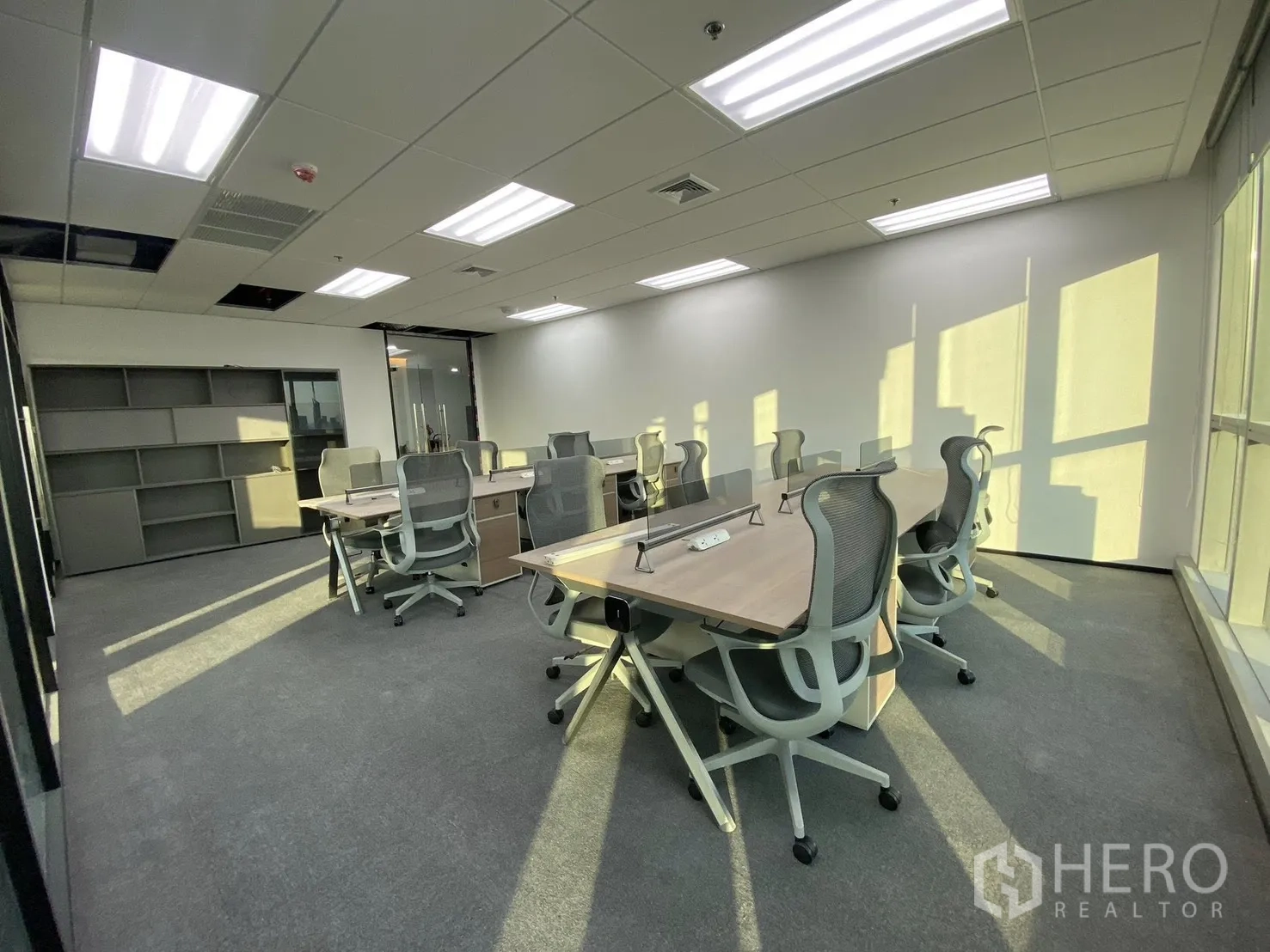 Office Space for rent in Huai Khwang, Bangkok - Open-plan workspace with rows of desks and ergonomic chairs, carpet flooring and bright daylight.