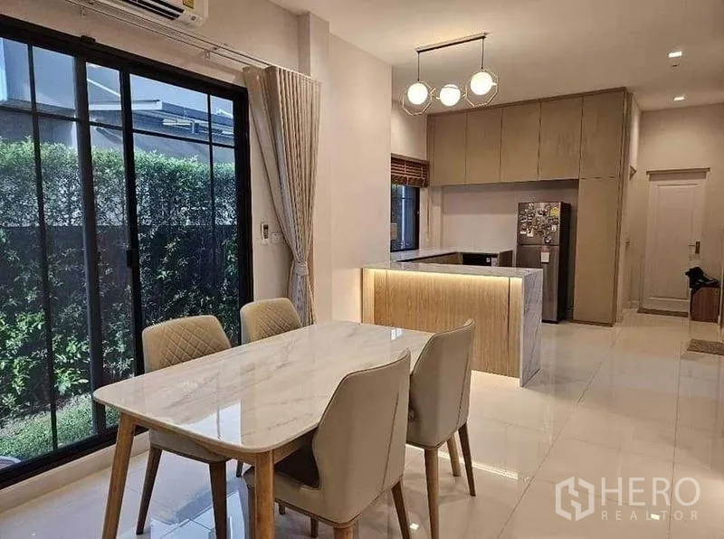Detached House for sale in Bang Kruai, Nonthaburi - Open-plan dining area beside sliding glass doors, adjoining a modern kitchen with island.