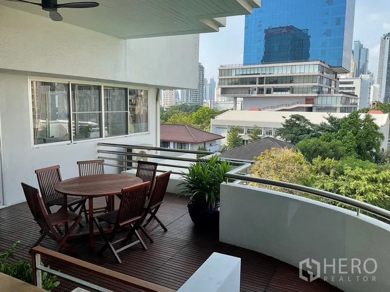 Apartment for rent in Sathon, Bangkok - Covered terrace with round table, planters and views of trees and towers.