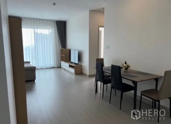 Condominium for rent in Bang Rak, Bangkok - Open-plan living room facing the balcony, TV stand and dining table for four.