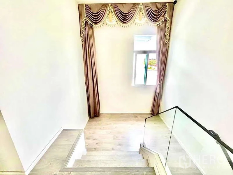 Detached House for rent in Prawet, Bangkok - Stair landing with decorative curtains, window and light wood flooring.