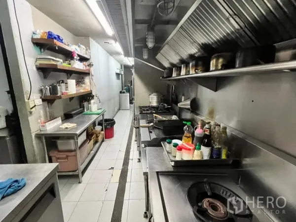 Retail Space for rent in Watthana, Bangkok - Commercial restaurant kitchen with stainless counters, range hoods, gas stoves and wall shelving.